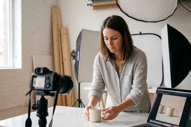 Photographe e-commerce arrangeant une tasse en céramique pour une prise de vue produit précise en studio minimaliste